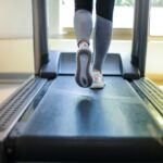 a woman in a black tee swings her arms as she runs on a treadmill