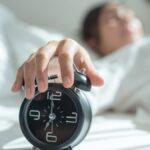 A woman hitting snooze on an alarm
