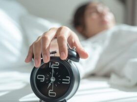 A woman hitting snooze on an alarm