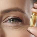 A middle aged woman hoping a fish oil pill next to her eye