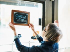 Senior female business owner turning open sign on door